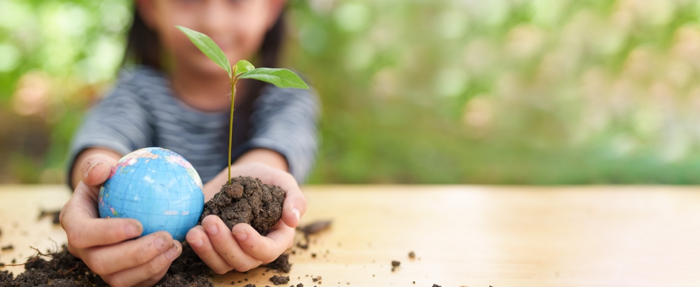 Little girl holding a plant and globe emphasizing animal well being, wildlife enclosures, and safety measures in the context of ESG and environmental education